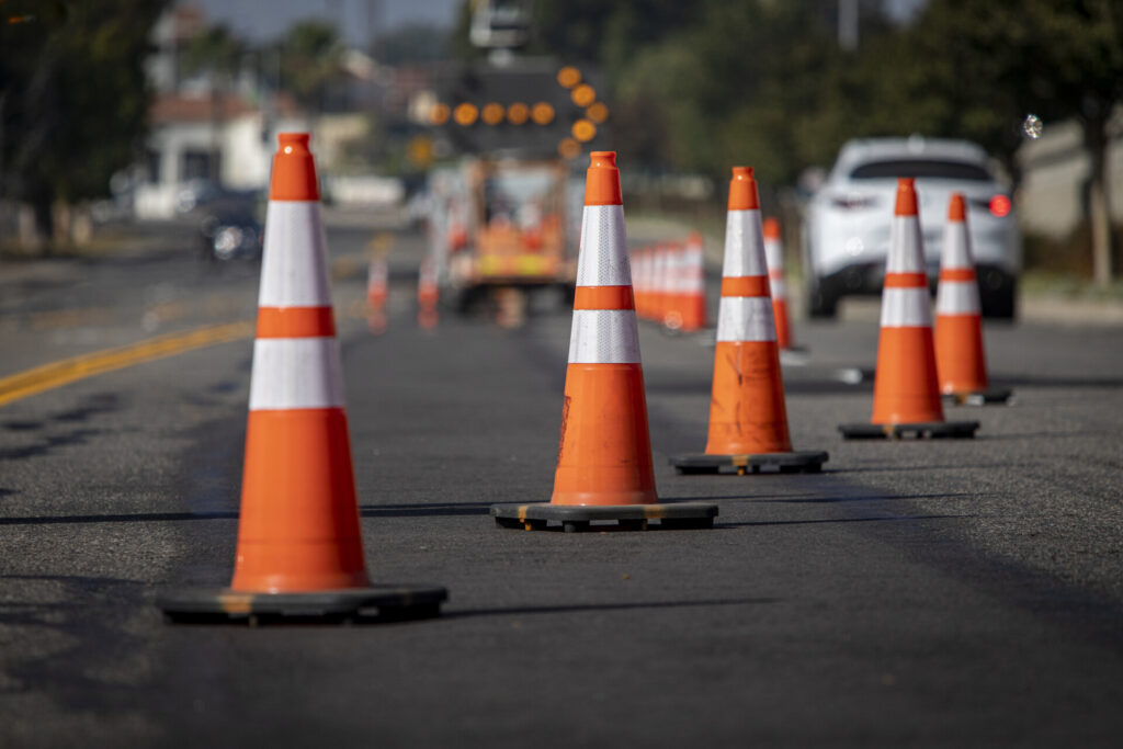 traffic cones on road with electronic arrow pointing to the right to divert traffic and white car in distance